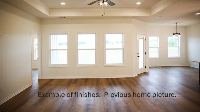 a large white kitchen with kitchen island a stove a sink a refrigerator and white cabinets with wooden floor