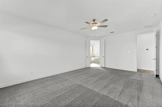 a view of an empty room with a ceiling fan and window