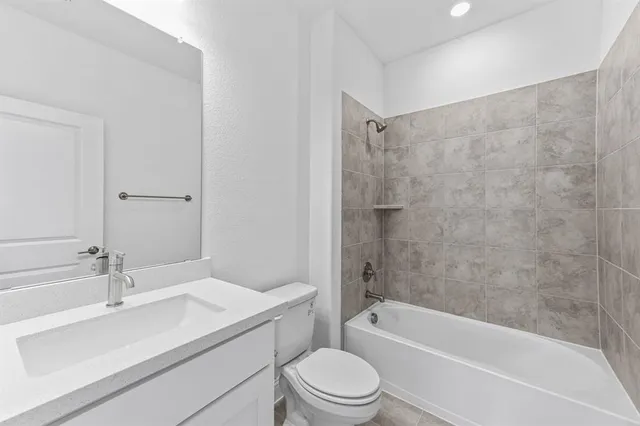 a bathroom with a bathtub shower sink vanity mirror and toilet