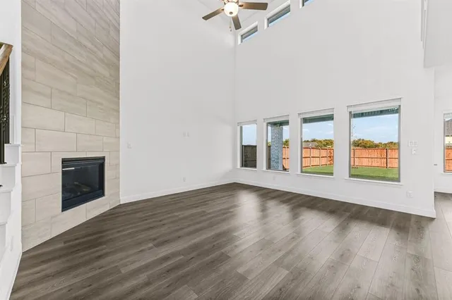 an empty room with wooden floor fireplace and windows
