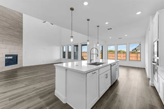 a kitchen with stainless steel appliances granite countertop a sink a stove and a wooden floors