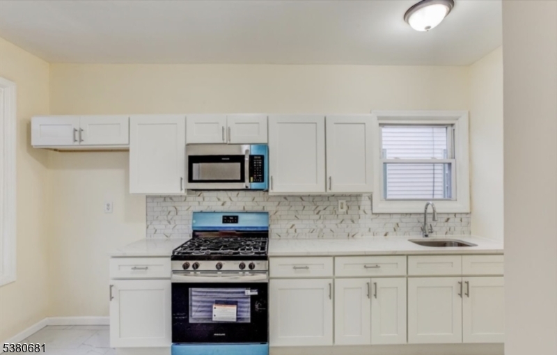 277 Wainwright Street Newark, NJ 07112 - Photo 6 of 11 a kitchen with granite countertop a stove a sink and a microwave