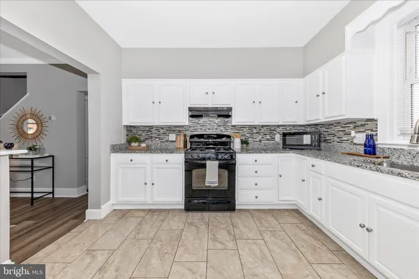 a kitchen with granite countertop a stove top oven sink and cabinets