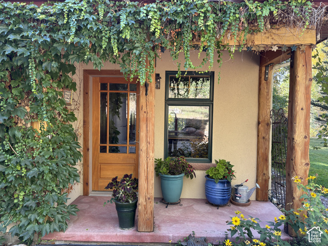725 Canyon Road Smithfield, UT 84335 - Photo 10 of 100 Wood-paneled entry door with transom windows, stucco exterior, and natural wood columns