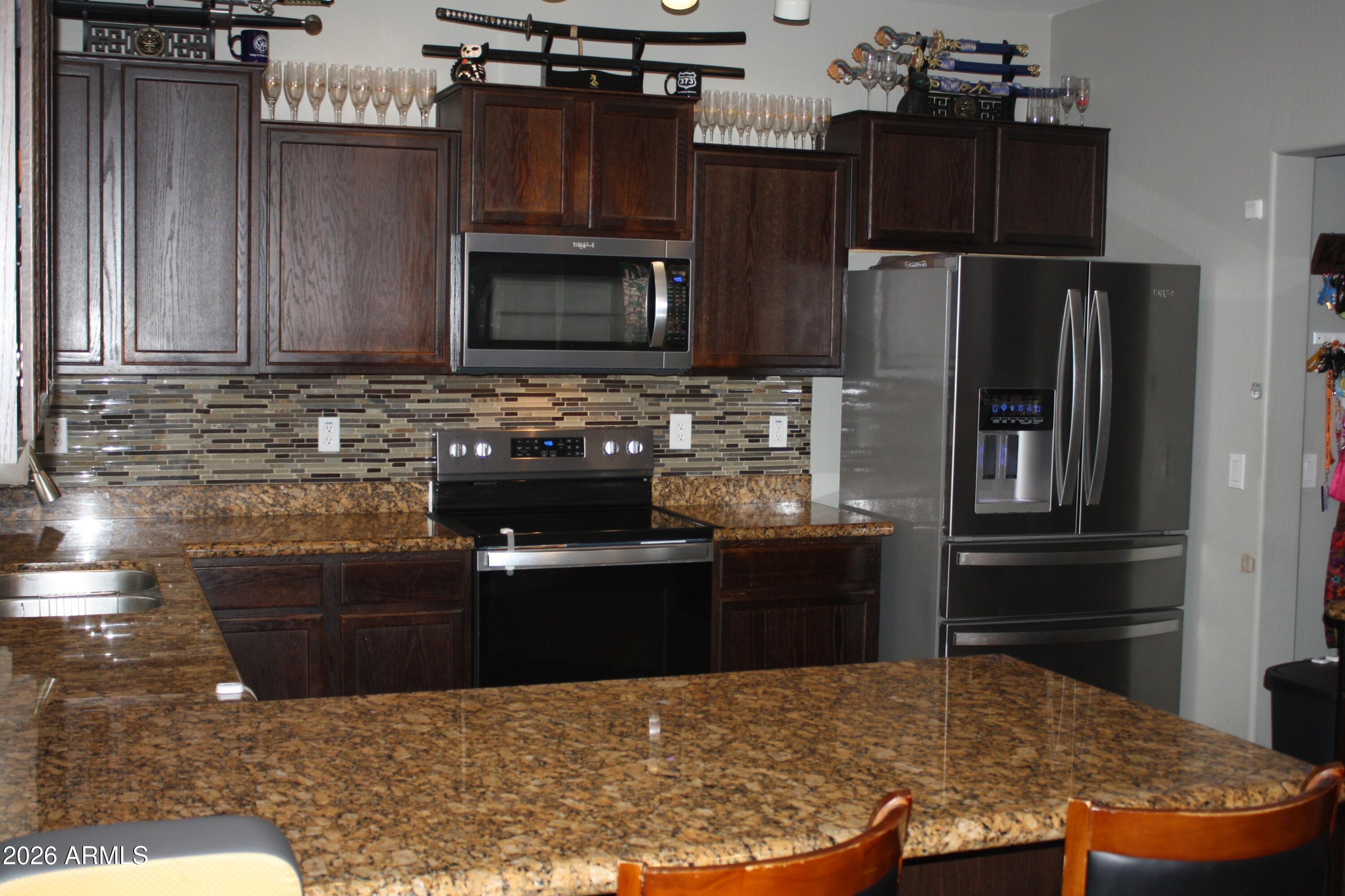 10225 West Camelback Road, Unit 19 Phoenix, AZ 85037 - Photo 10 of 51 a kitchen with kitchen island granite countertop a refrigerator stove and microwave