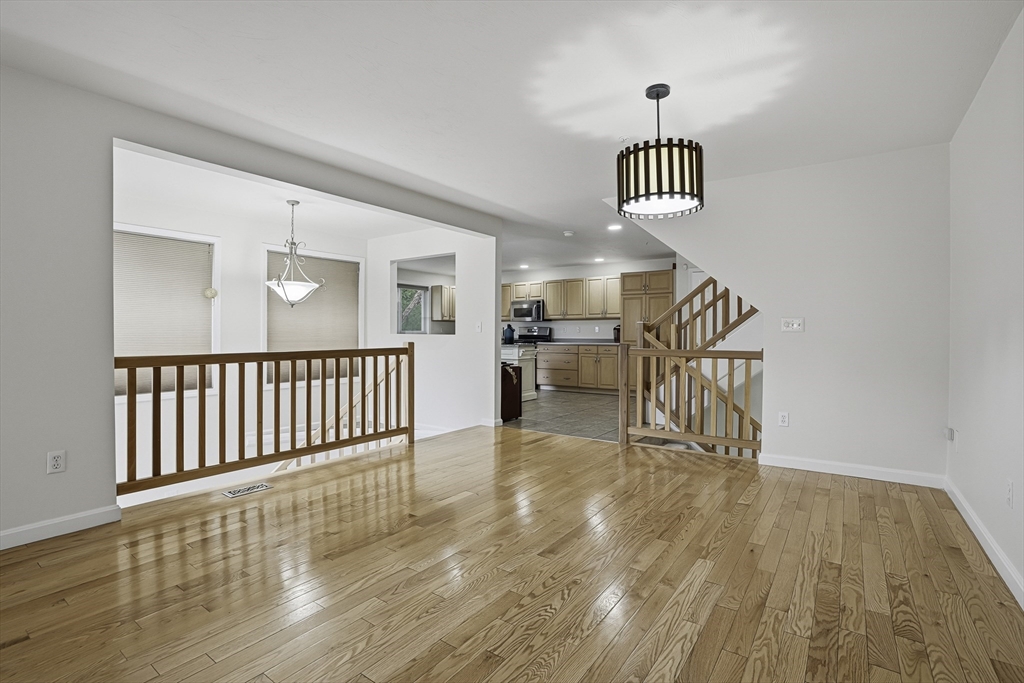 153 America Boulevard, Unit 153 Ashland, MA 01721 - Photo 12 of 42 a view of a hallway with wooden floor and a chandelier