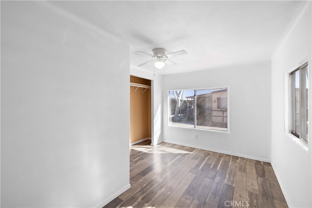 43850 20th Street East, Unit 265 Lancaster, CA 93535 - Photo 13 of 19 an empty room with wooden floor chandelier fan and windows
