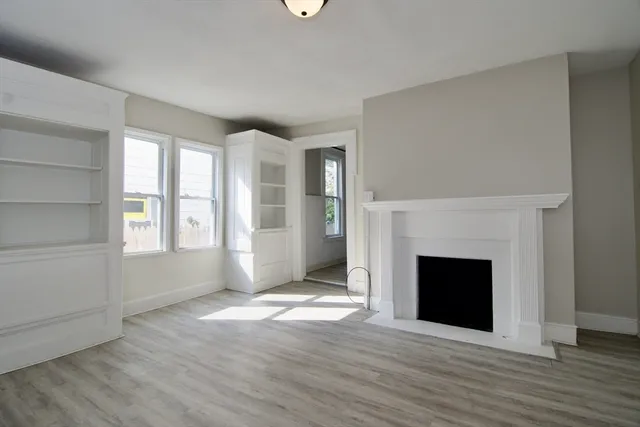 an empty room with windows and fireplace