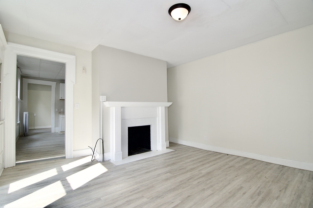 58 Howes Street, Unit 1 Springfield, MA 01118 - Photo 4 of 24 a view of empty room with wooden floor and fireplace