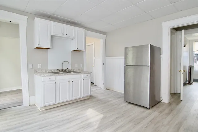 a kitchen with white cabinets and refrigerator
