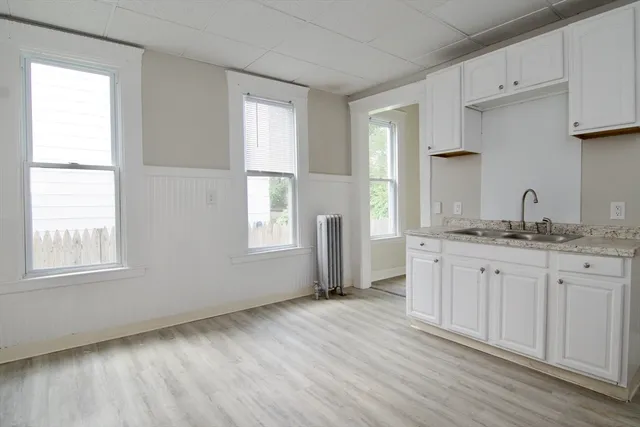 a kitchen with granite countertop white cabinets and wooden floor