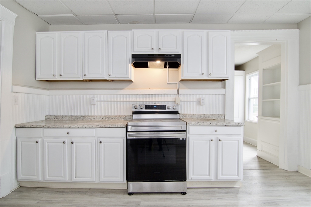 58 Howes Street, Unit 1 Springfield, MA 01118 - Photo 8 of 24 a kitchen with granite countertop white cabinets and stainless steel appliances