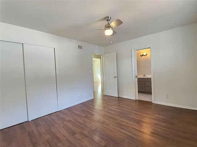 a view of an empty room with wooden floor and closet