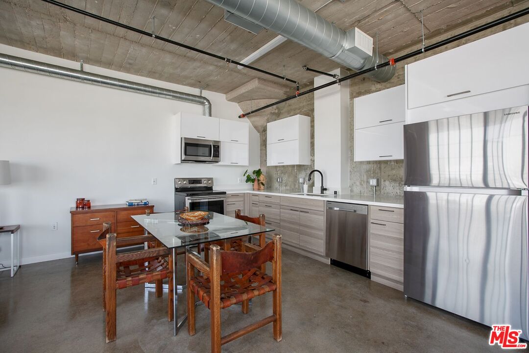 691 Mill Street, Unit 705 Los Angeles, CA 90021 - Photo 7 of 11 a kitchen with stainless steel appliances granite countertop a dining table chairs refrigerator and microwave