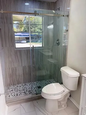 a bathroom with a toilet a sink a shower and a window