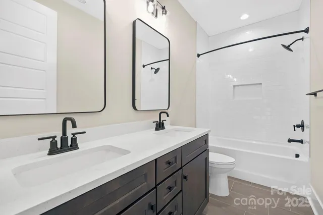a bathroom with a double vanity sink a toilet and a bathtub
