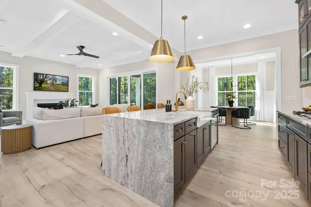 a large kitchen with kitchen island a large counter top space a sink a window a flat screen tv and stainless steel appliances