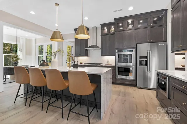 a kitchen with stainless steel appliances a dining table chairs stove refrigerator and cabinets