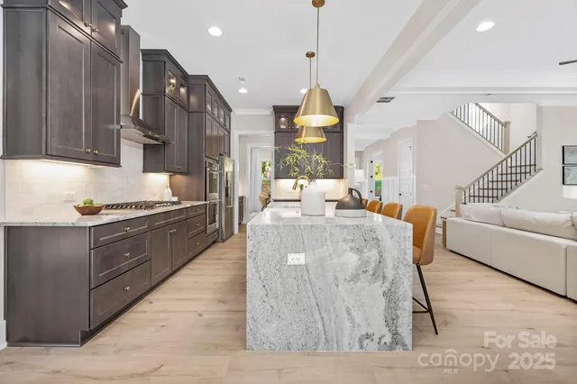 a large kitchen with stainless steel appliances kitchen island granite countertop a table chairs in it and a window