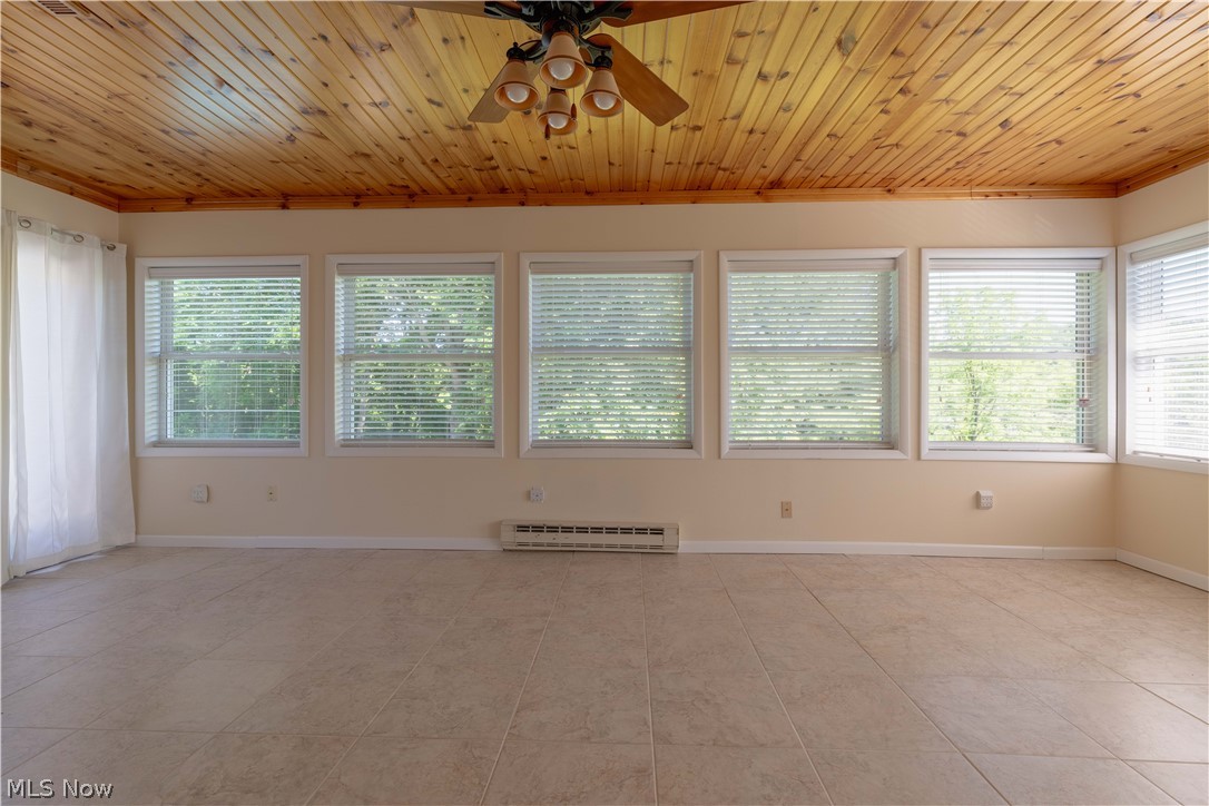 3963 Mark Road Cambridge, OH 43725 - Photo 33 of 50 Tiled empty room with a baseboard heating unit, a healthy amount of sunlight, ceiling fan, and wooden ceiling