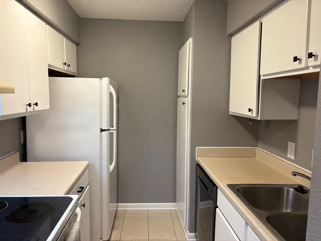 a kitchen with a sink a refrigerator and cabinets