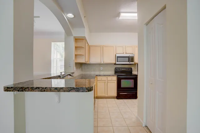 a kitchen with granite countertop a refrigerator and a stove top oven