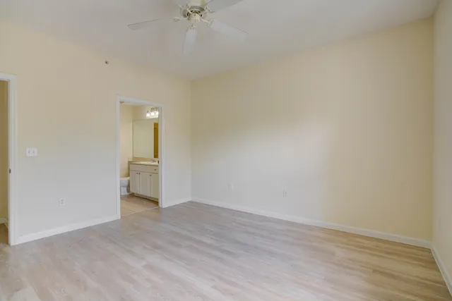 an empty room with wooden floor fan and windows