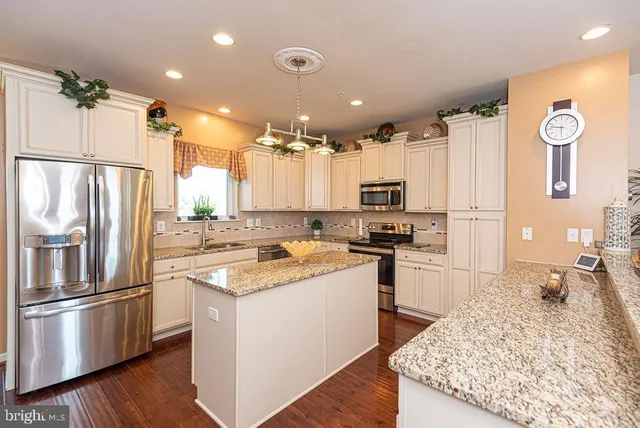 a kitchen with kitchen island granite countertop a sink cabinets and stainless steel appliances