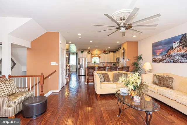 a kitchen with stainless steel appliances granite countertop a kitchen island a stove a refrigerator and a dining table with wooden floor