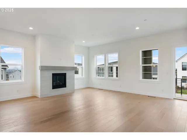 a view of an empty room with wooden floor and windows