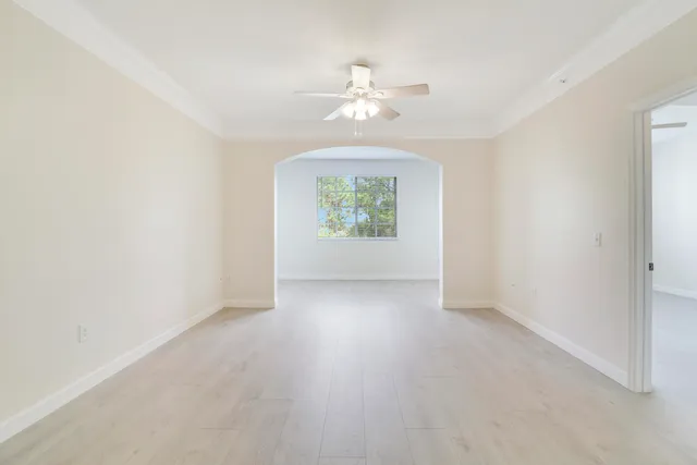 an empty room with windows and chandelier fan