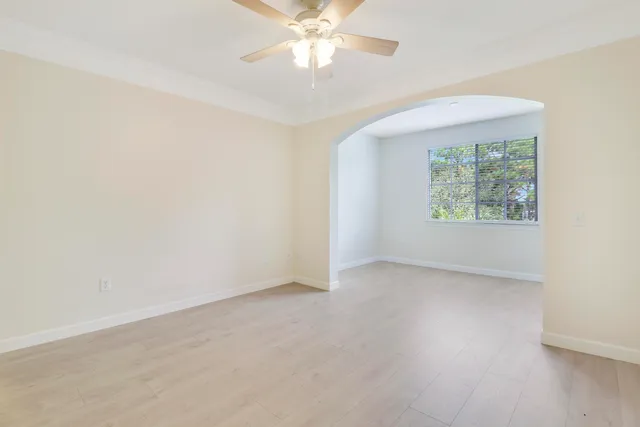 an empty room with windows and ceiling fan