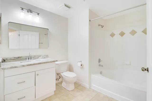 a bathroom with a granite countertop sink a toilet and a bathtub