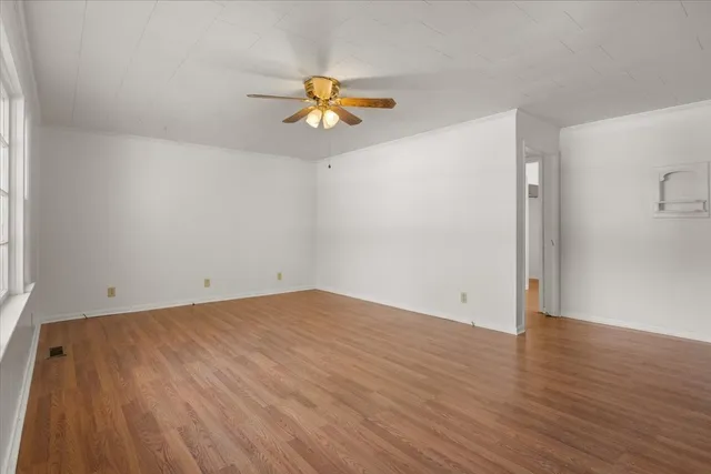 an empty room with windows and chandelier fan