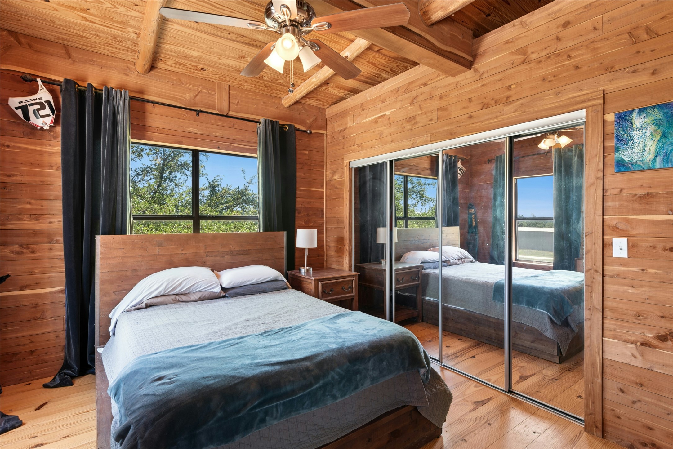 496 Middleton Road Spicewood, TX 78669 - Photo 23 of 40 Bedroom featuring wood plank walls, exposed wood ceiling beams, and wood-finish flooring