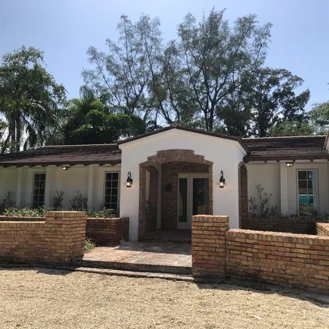a view of a white house with large windows and a small yard