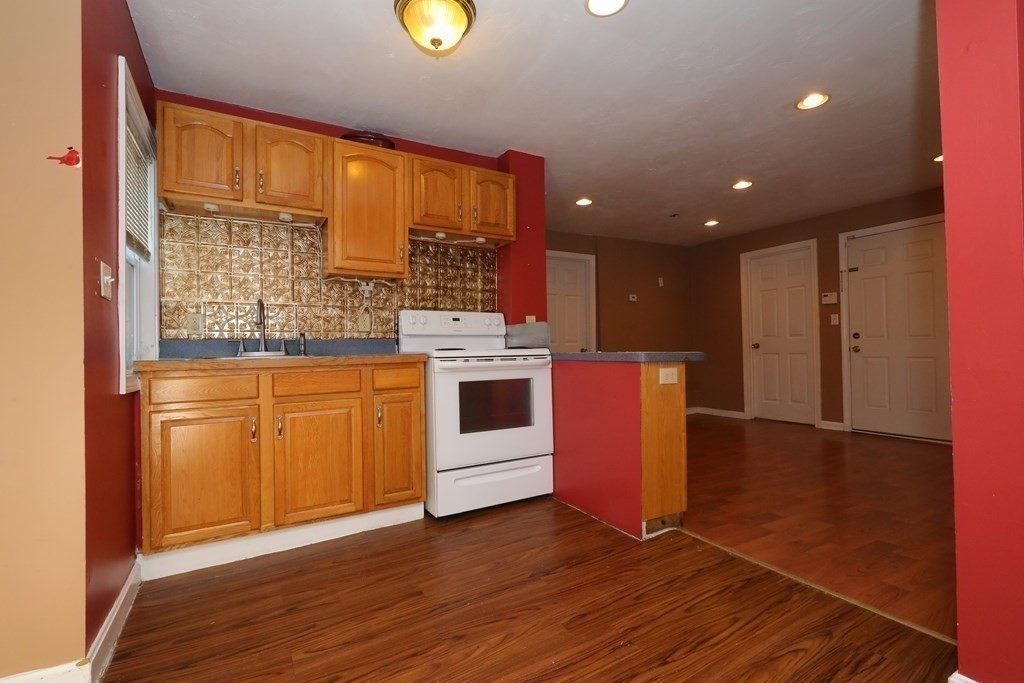 a kitchen with stainless steel appliances granite countertop a stove a sink and a refrigerator with wooden floors