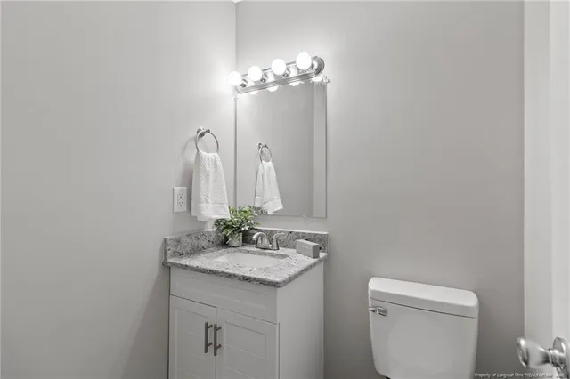 a bathroom with a granite countertop sink a toilet and a mirror