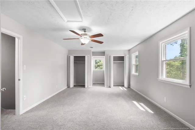 an empty room with windows and fan