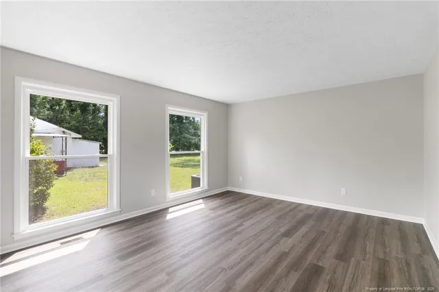an empty room with wooden floor and windows