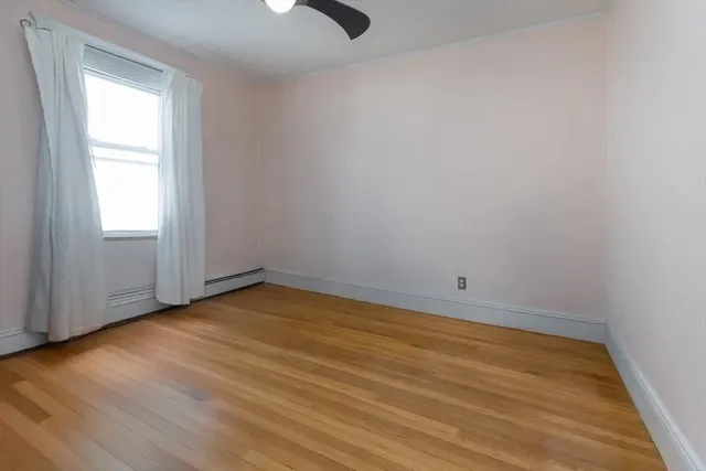 an empty room with wooden floor cabinet and windows