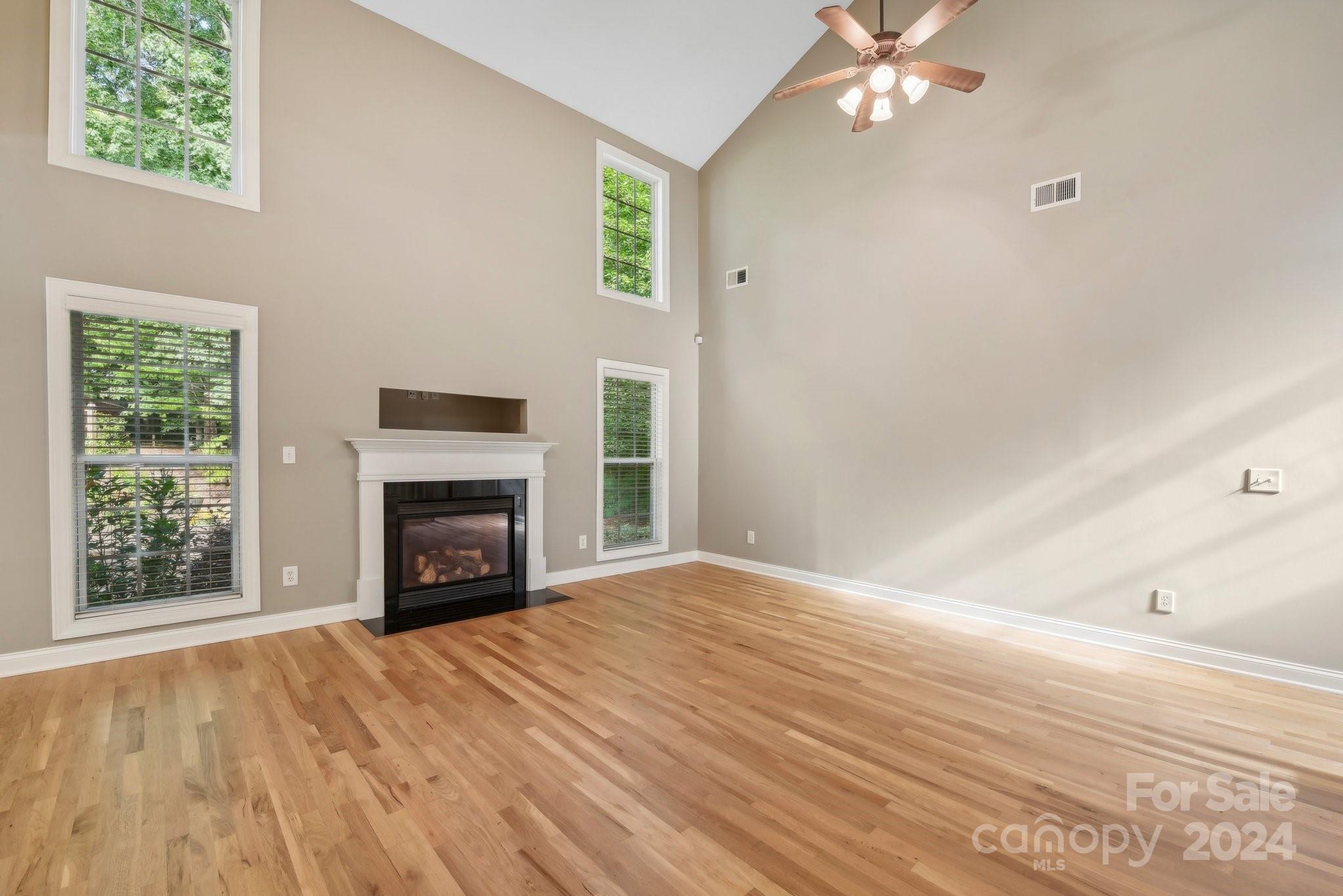 1013 Wesley Downs Road Monroe, NC 28110 - Photo 10 of 41 an empty room with windows fireplace and wooden floor