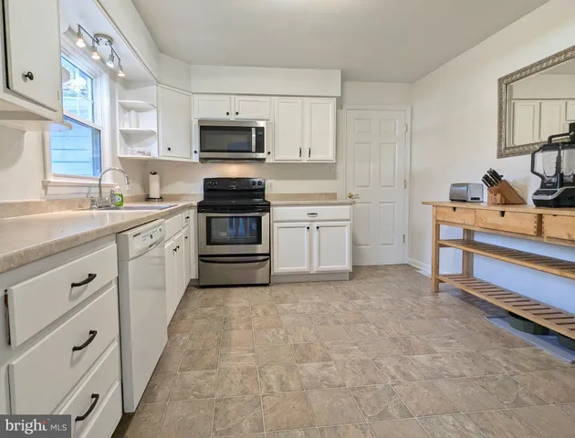 a kitchen with granite countertop white cabinets stainless steel appliances and a sink