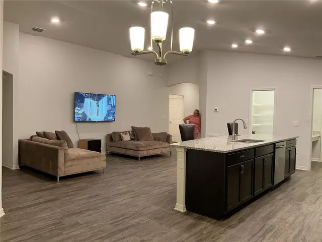 a kitchen with stainless steel appliances granite countertop a sink dishwasher a stove and a dining table with wooden floor