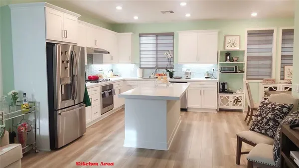 a kitchen with stainless steel appliances a refrigerator a sink a stove a dining table and chairs