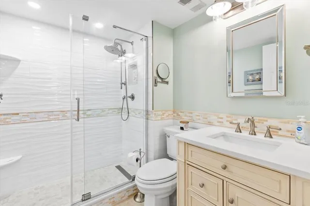 a bathroom with a granite countertop sink a toilet and shower