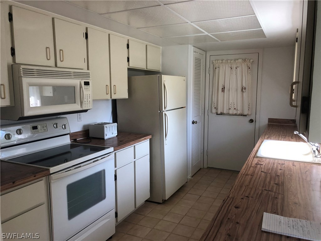 358 Delaware Road Lehigh Acres, FL 33936 - Photo 3 of 22 a kitchen with cabinets stainless steel appliances and wooden floor