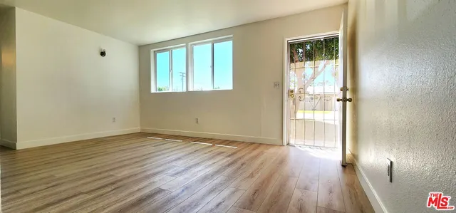a view of an empty room with wooden floor and a window
