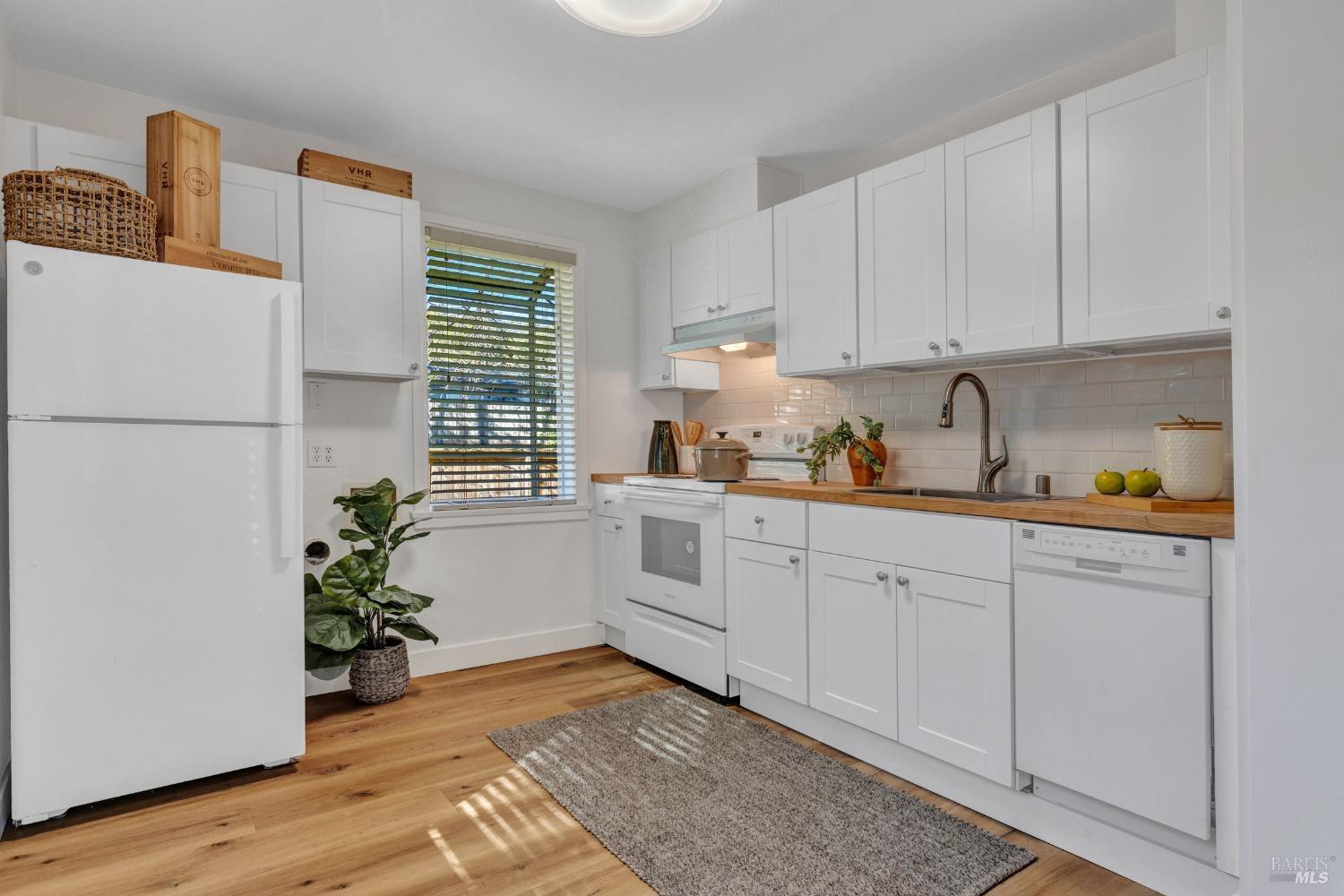 a kitchen with white cabinets and wooden floor