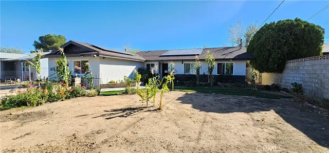 a dirt road with an house wooden fence and trees in the background